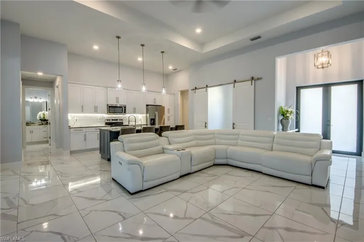 Living area featuring recessed lighting, a barn door, marble finish floor, visible vents, and a towering ceiling