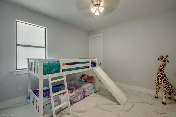 Bedroom featuring baseboards, ceiling fan, and marble finish floor