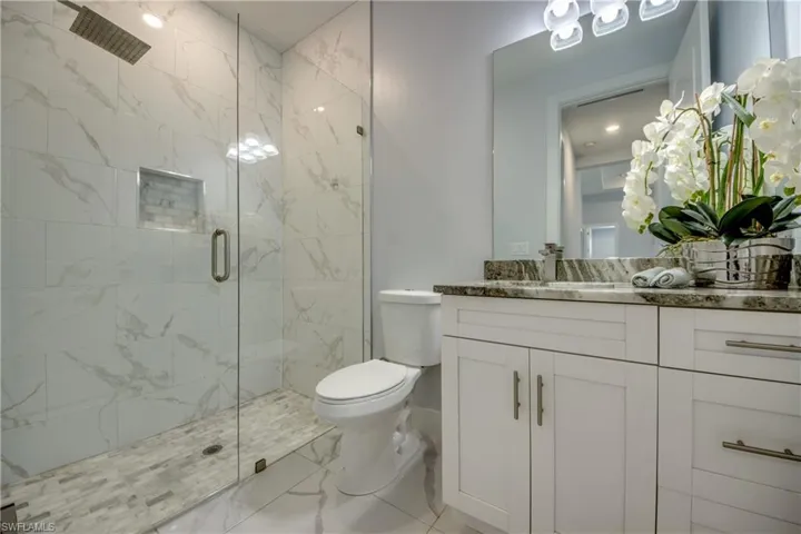 Full bath featuring a stall shower, vanity, toilet, and marble finish floor