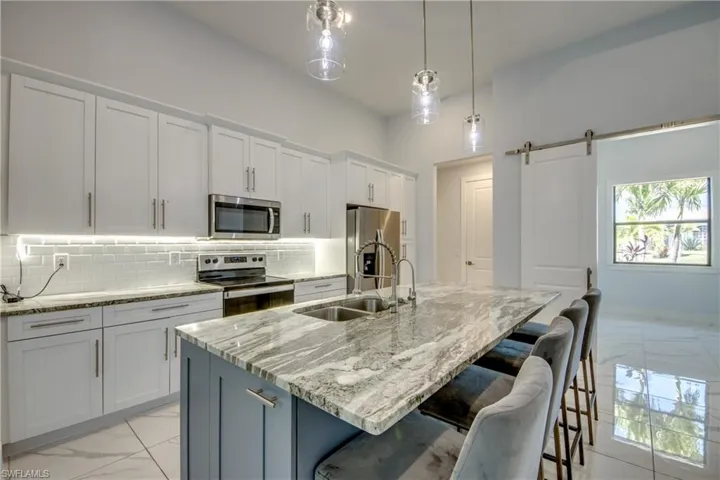 Kitchen featuring backsplash, marble finish floor, a sink, and appliances with stainless steel finishes