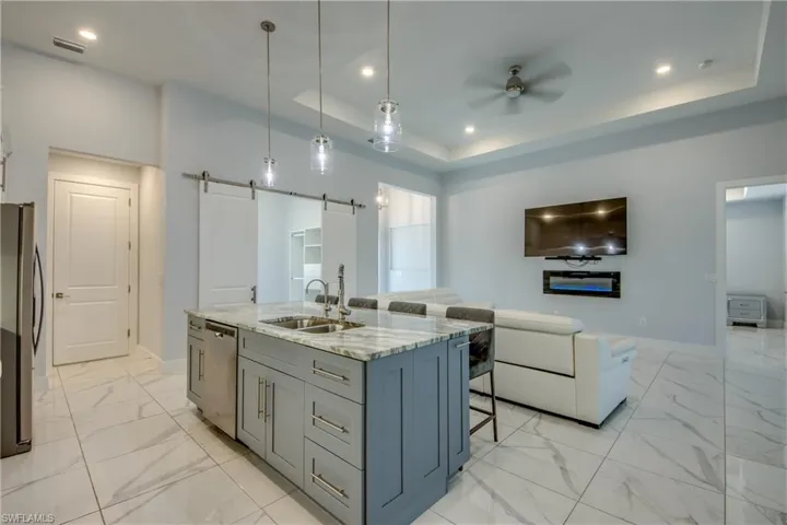Kitchen featuring ceiling fan, stainless steel appliances, a tray ceiling, and marble finish floor