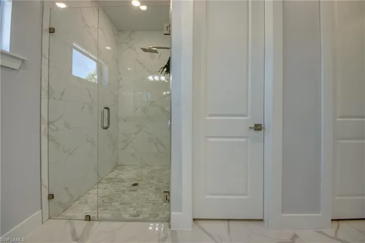 Full bath with a marble finish shower, marble finish floor, and baseboards
