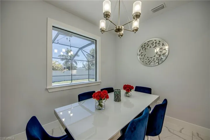 Dining room featuring marble finish floor, an inviting chandelier, baseboards, and visible vents