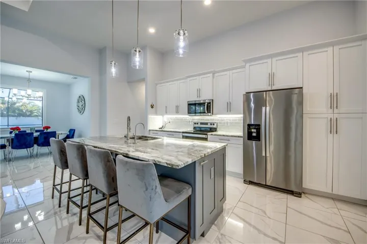 Kitchen featuring a sink, stainless steel appliances, decorative backsplash, a breakfast bar area, and marble finish floor