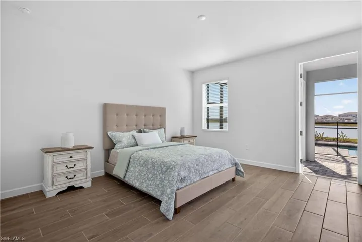 This room features a window with blinds and access to a paved outdoor area, which overlooks a body of water and distant properties