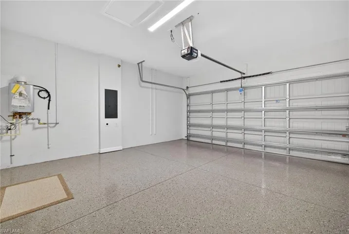 The garage features a concrete floor with a speckled finish, an automatic garage door opener, and a wall-mounted water heater