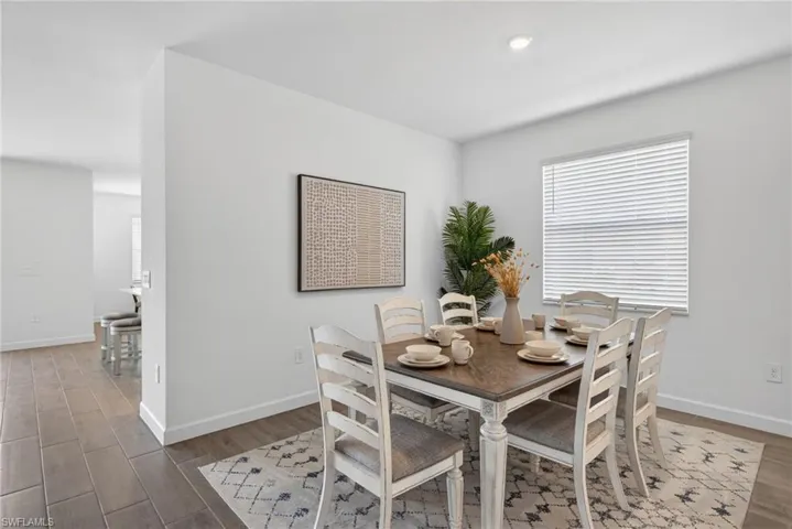The dining area features white walls, recessed lighting, and a window with white blinds