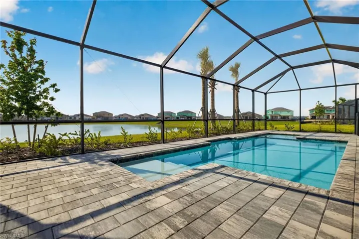 The property features a screened-in swimming pool with a paved deck, overlooking a body of water and distant houses