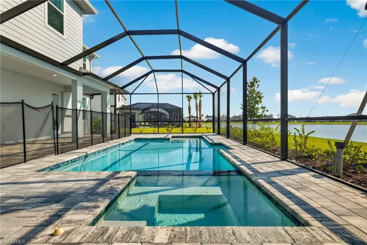 The property features a screened-in swimming pool and integrated spa, surrounded by pavers
