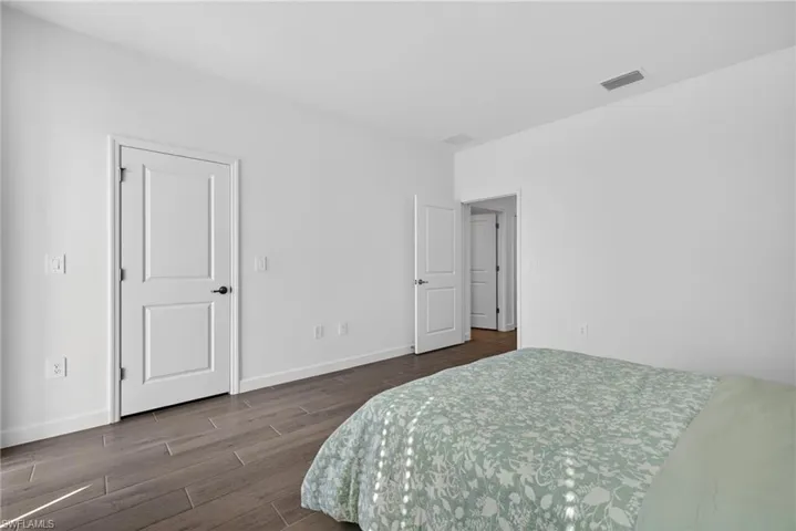 Well-lit room featuring light-colored walls, wood-look flooring, and white interior doors