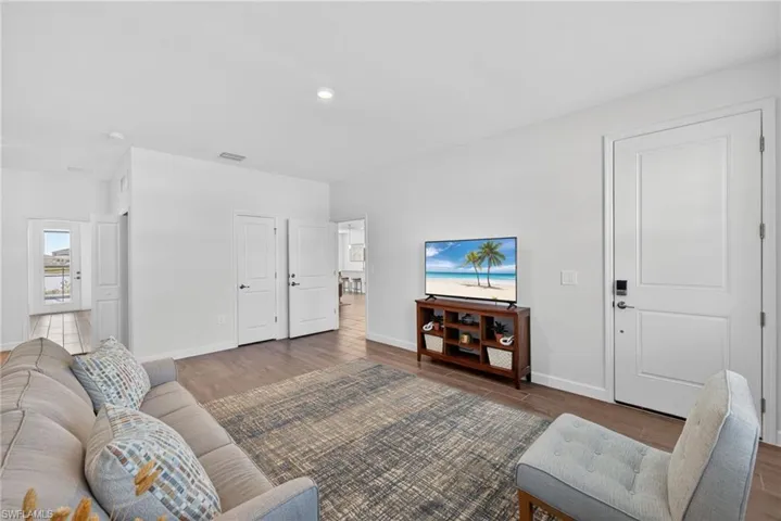 The inviting living area features light-toned walls, recessed lighting, and wood-look flooring