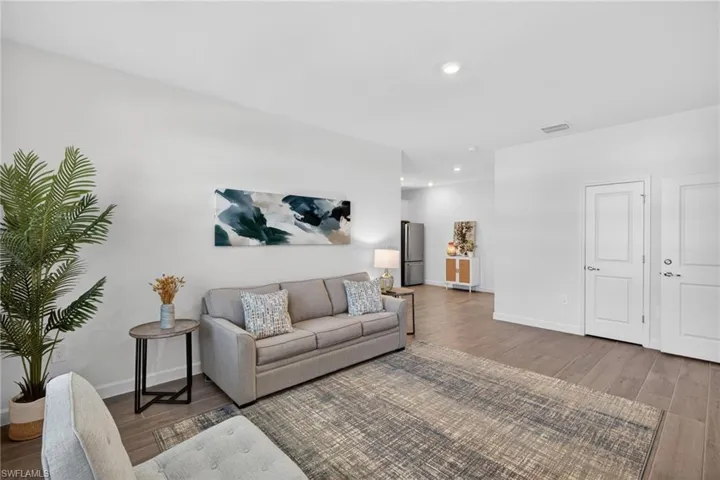 Living space featuring light-colored walls, recessed lighting, and wood-look flooring