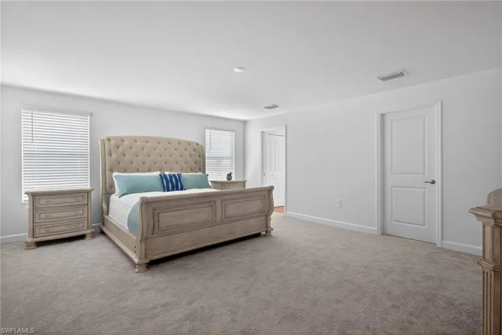 This spacious room features neutral-toned carpet flooring and white walls, creating a bright and open feel