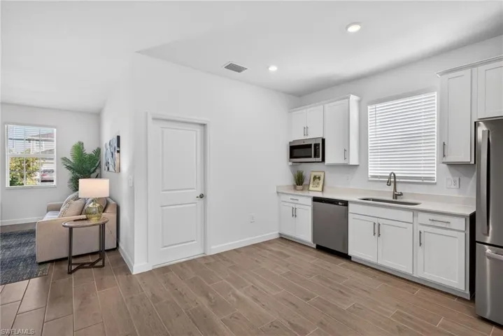 Kitchen area featuring white cabinetry, stainless steel appliances, and a window with blinds