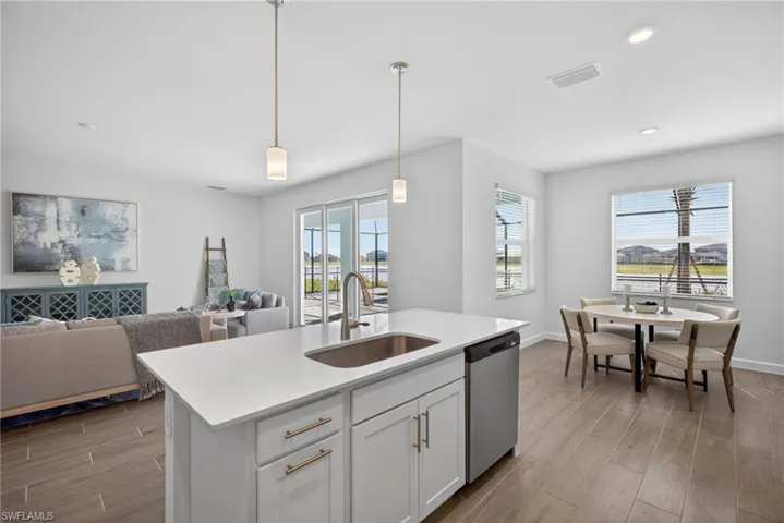 Kitchen island with white countertops, an undermount sink, and pendant lighting