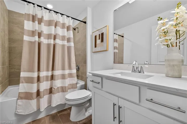 This bathroom features a white vanity with a white countertop and a single sink, complemented by a large mirror