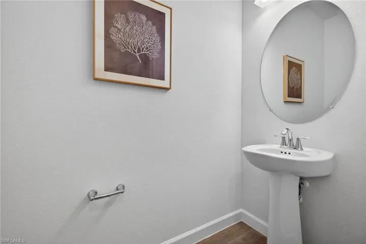This space features a pedestal sink with a chrome faucet, a large oval mirror, and light-colored walls