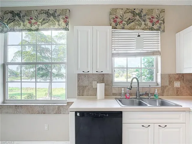 Kitchen with dishwasher, tasteful backsplash, sink, and white cabinets