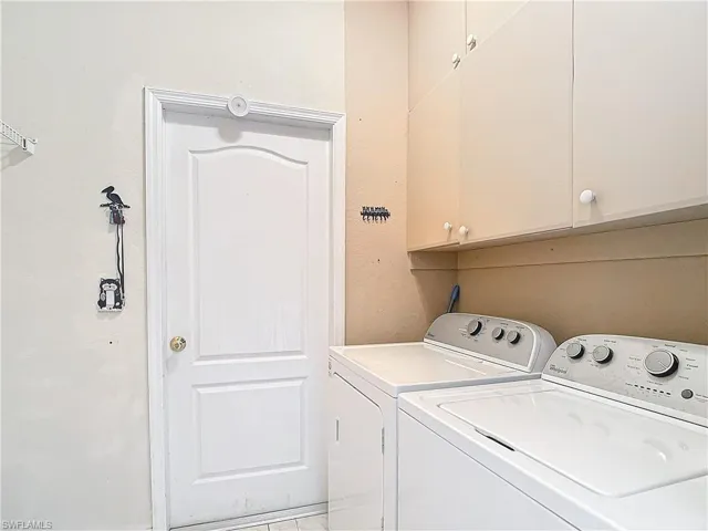 Laundry area featuring washing machine and clothes dryer and cabinets