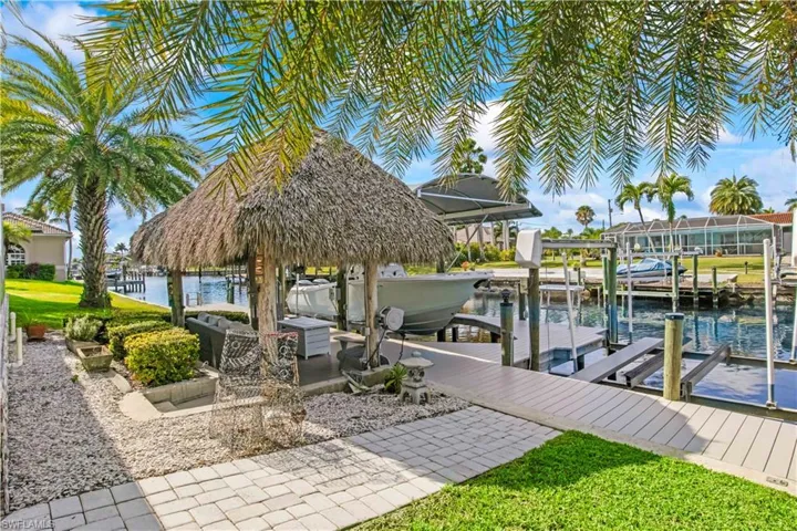 Private dock with boat lift and waterside tiki hut for canal-side relaxation.