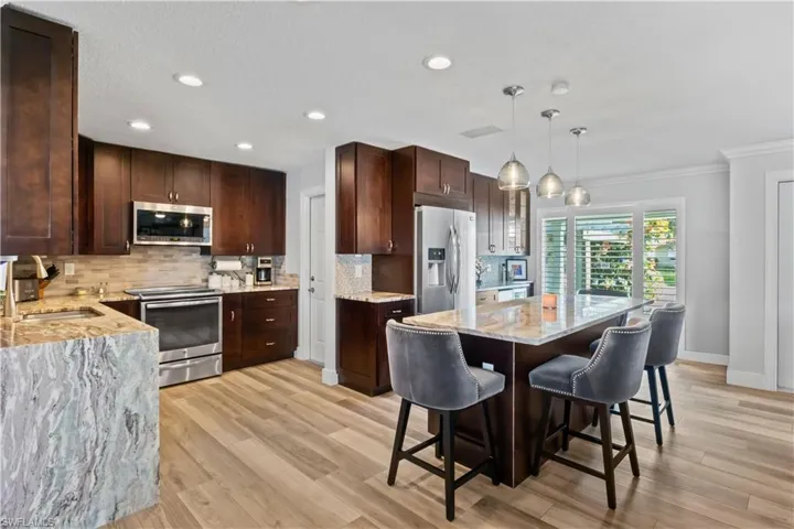 Updated kitchen with wood cabinetry, granite countertops, stainless-steel appliances, and a huge breakfast bar.