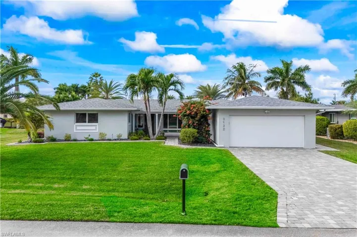 Front view capturing the home’s curb appeal, oversized lot, and tropical surroundings.