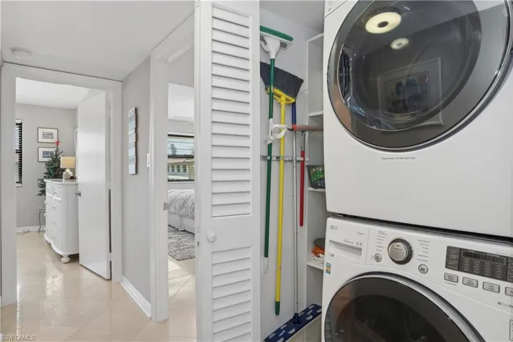 Laundry area featuring light tile patterned flooring and stacked washing maching and dryer