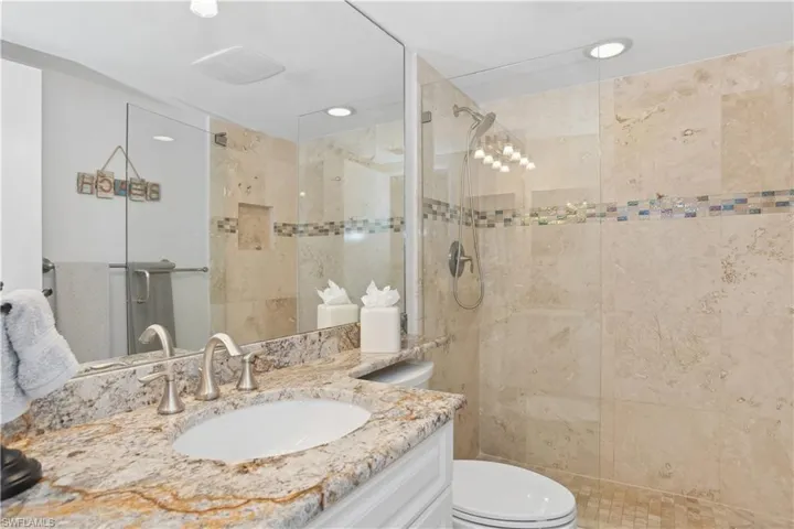 Bathroom featuring vanity, toilet, and a tile shower