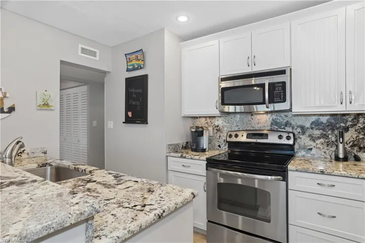 Kitchen featuring white cabinets, decorative backsplash, sink, and appliances with stainless steel finishes