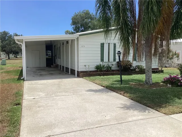 Manufactured / mobile home with a front lawn and a carport