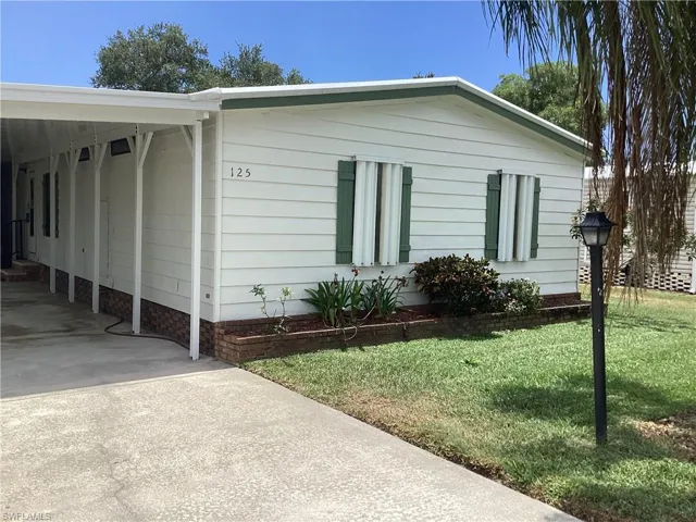 View of side of property with a carport and a yard