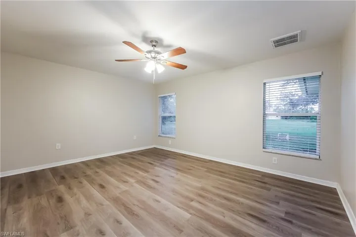 Spare room with wood finished floors, plenty of natural light, and ceiling fan
