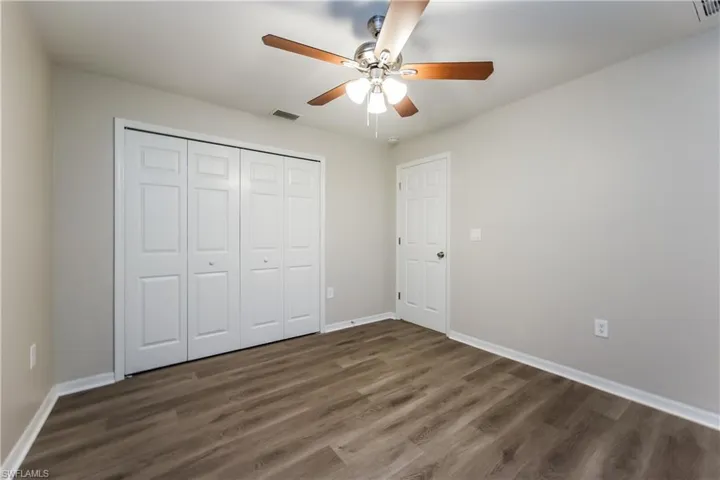 Unfurnished bedroom featuring dark wood-type flooring, ceiling fan, and a closet