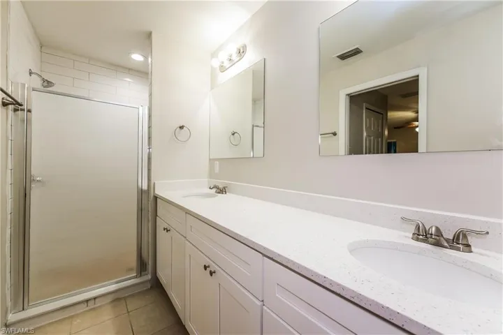 Bathroom featuring double vanity, a shower stall, light tile patterned floors, recessed lighting, and a ceiling fan