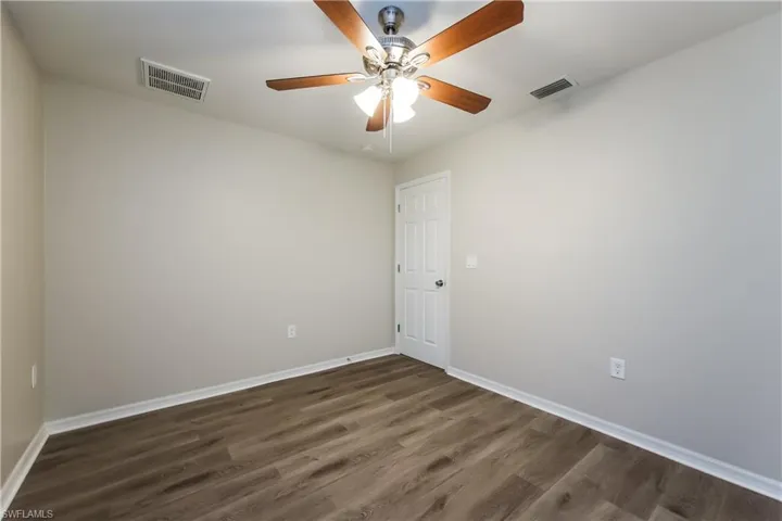 Unfurnished room with dark wood-style flooring and a ceiling fan