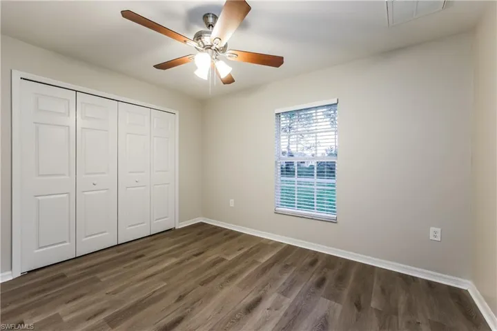 Unfurnished bedroom featuring dark wood-style floors, a closet, and a ceiling fan