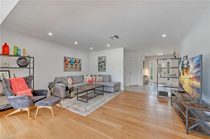 Living room with light wood-style floors, visible vents, and recessed lighting