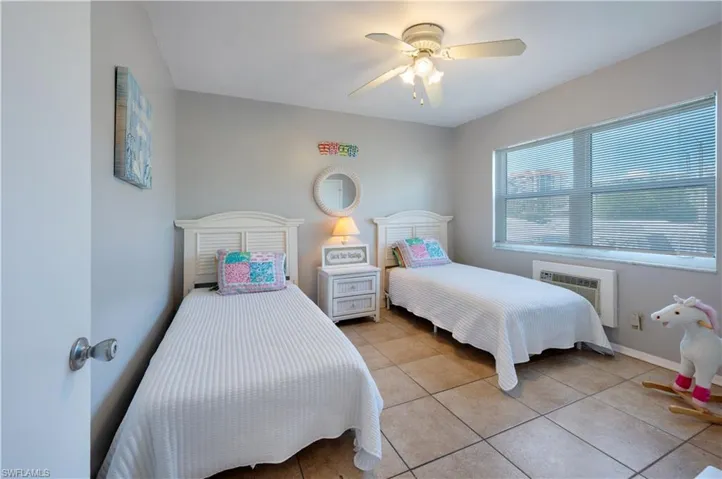 Bedroom #2 with light tile patterned floors, a ceiling fan, and a wall unit AC