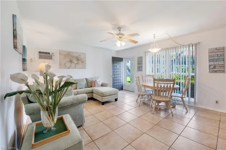 Living area featuring light tile patterned floors, a ceiling fan, and a wall mounted air conditioner