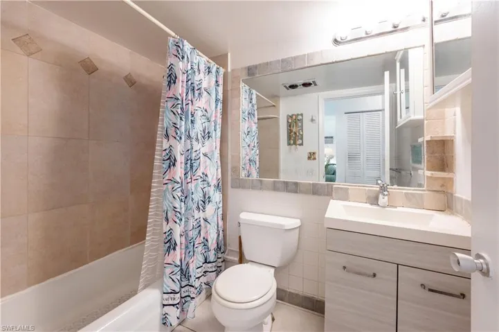 Bathroom featuring shower / bath combo, tile walls, and vanity