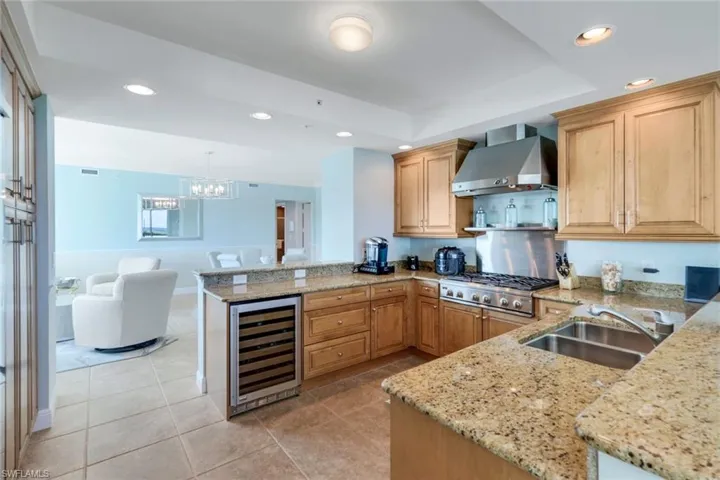 Large kitchen with stainless steel appliances, gas cooktop, warming shelf and beverage fridge