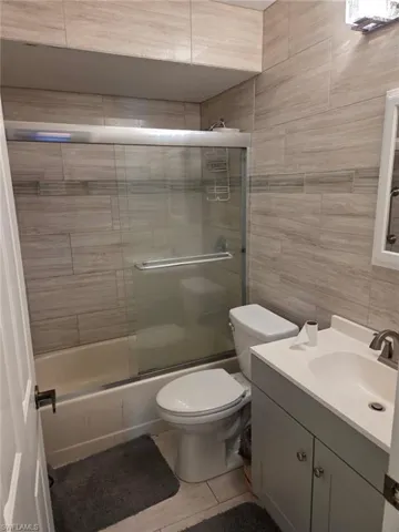 Bathroom with vanity, tile walls, and shower / bath combination with glass door