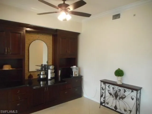Kitchen with crown molding, ceiling fan, open shelves, light tile patterned floors, and dark brown cabinetry