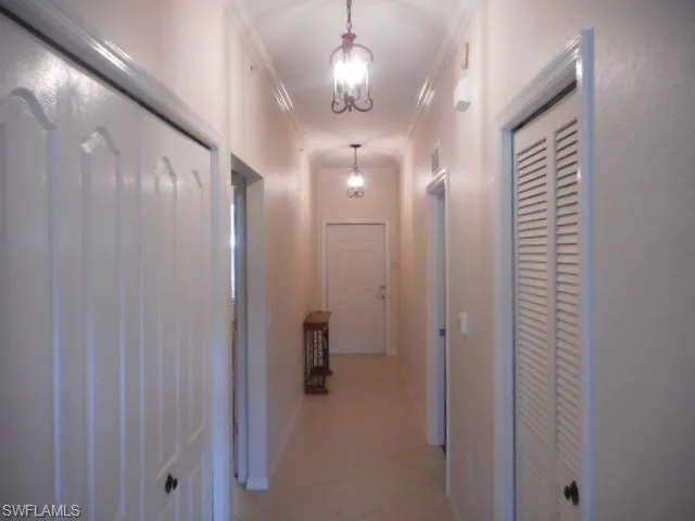 Hall featuring crown molding and light tile patterned flooring