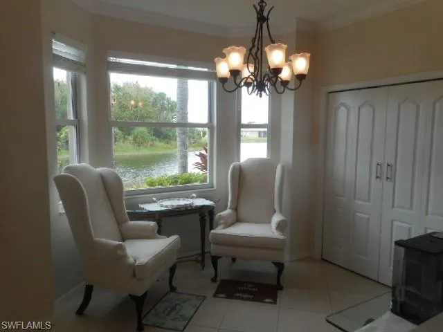 Sitting room featuring ornamental molding, light tile patterned floors, a water view, a chandelier, and a wood stove