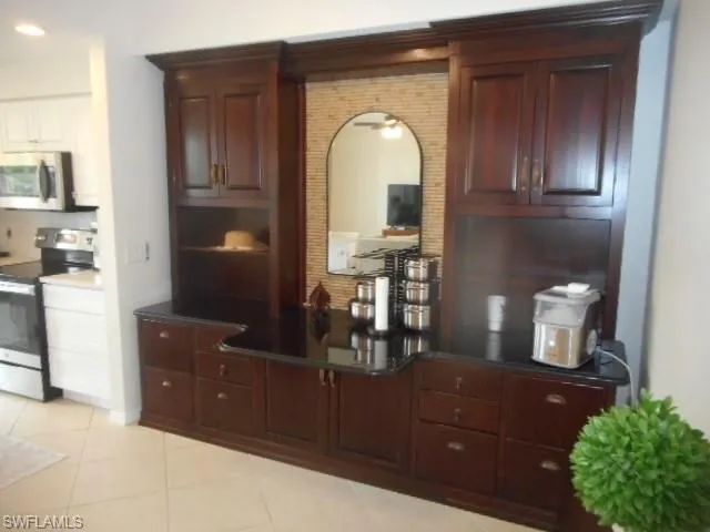 Kitchen featuring stainless steel appliances, dark brown cabinets, and light tile patterned floors