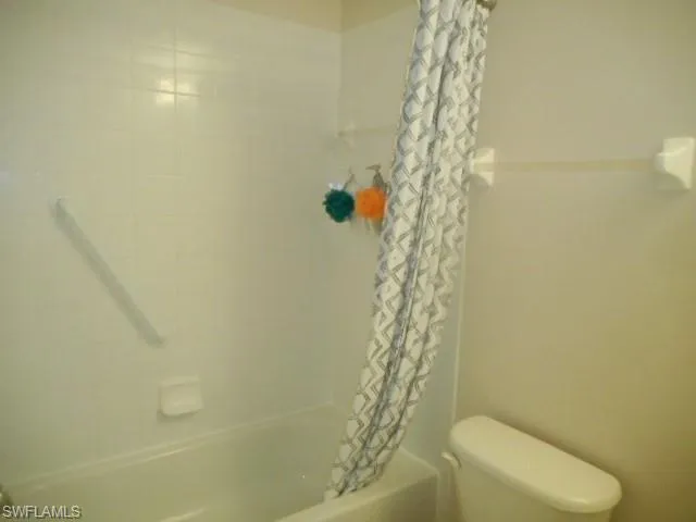 Full bath featuring shower / bath combo with shower curtain and toilet