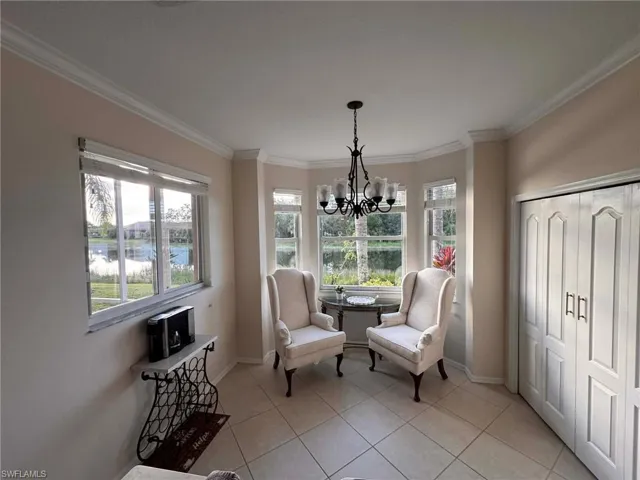 Sitting room with crown molding, light tile patterned floors, a water view, and a chandelier