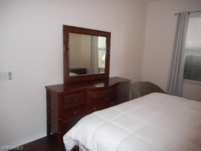 Bedroom featuring dark wood-type flooring and baseboards