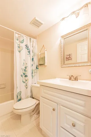 Full bathroom featuring tile patterned floors, toilet, shower / tub combo with curtain, vanity, and visible vents